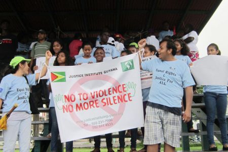 Participants in the Justice Institute Guyana ‘Walk for Equality’ hoist their banner, at the closing held at Parade Ground on Sunday.
