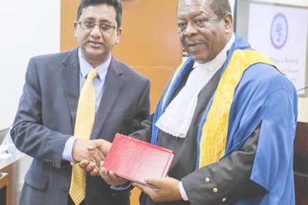 Attorney General Anil Nandall (left) yesterday handed over copies of Guyana Law Books and Law Reports to the Caribbean Court of Justice (CCJ), following a special sitting in honour of Justice Desiree Bernard. In this Arian Browne photo, Nandlall hands over one of the books to President of the CCJ, Sir Dennis Byron.