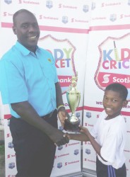 Coordinator Colin Stuart presents the winner’s trophy for the South Georgetown Zone to Captain of the South Ruimveldt Primary School cricket team Oshazay Savory. 