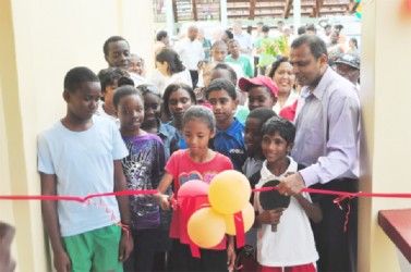 Minister of Sport, Dr. Frank Anthony watches on as a young sportswoman symbolically cuts the ribbon to open the National Resource Centre. (Orlando Charles photo) 