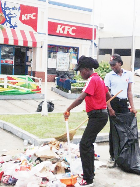KFC workers cleaning away garbage yesterday following heavy partying on the business’s premises on Mashramani Day 