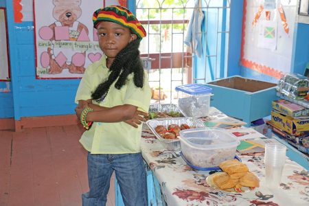 Representing the land of reggae: A Starters Nursery School pupil decked out with his Tam and locks stands near a table with Jamaican cuisine at the school’s Commonwealth Day activity. Commonwealth Day was observed two Mondays ago under the theme ‘Team Commonwealth’. (Photo by Arian Browne)