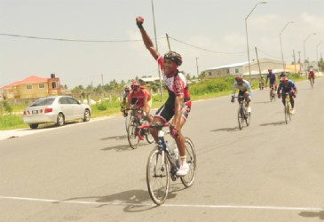 Double winner Michael Anthony raises his hand in  triumph after winning the first stage of the 17th annual Dr Cheddi Jagan Memorial cycle road race in West Demerara yesterday. (Orlando Charles photo)