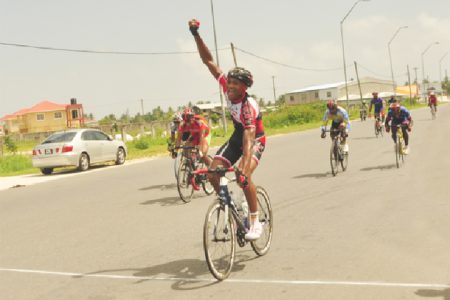 Double winner Michael Anthony raises his hand in  triumph after winning the first stage of the 17th annual Dr Cheddi Jagan Memorial cycle road race in West Demerara yesterday. (Orlando Charles photo)