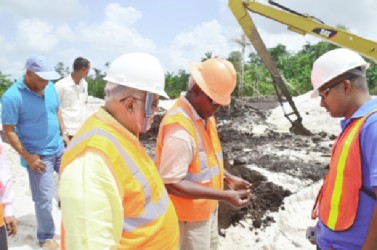 President Donald Ramotar (left) and Minister of Public Works, Robeson Benn (second from left) inspecting soil at the airport (GINA photo)