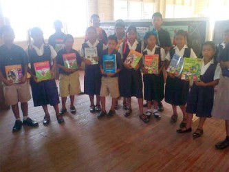 Wearing their new shoes, some of the pupils pose with some of the books also donated by Digicel 