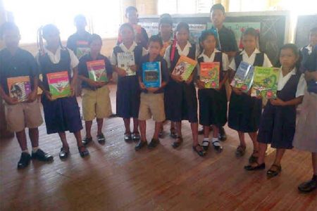 Wearing their new shoes, some of the pupils pose with some of the books also donated by Digicel

