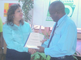 Education Minister Priya Manickchand presents one of the contracts to University of Guyana Vice-Chancellor Jacob Opadeyi.  