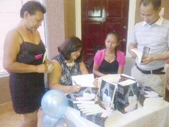 Julia Kanhai signing copies her recent book launch.