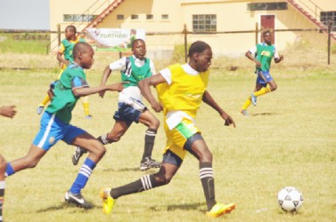 Marlon Nedd of Carmel Secondary (yellow) on the attack against Kingston Secondary in their matchup