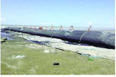 Ministry of Public Works technicians installing the first geotextile tube groyne to be constructed at the Kingston – Kitty foreshore (Photo courtesy Ministry of Public Works)