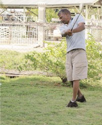 Ruplall Dudnauth taking a  swing at a golf ball in his yard.