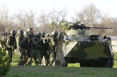 Armed men, believed to be Russian servicemen, take cover behind an armoured vehicle as they attempt to take over a military airbase in the Crimean town of Belbek near Sevastopol yesterday. (Reuters)