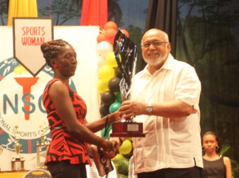 His Excellency President Donald Ramotar handing over the senior sportswoman of the year award to the mother of Shemaine Campbell. 
