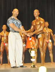 HRC, Chairman, Hugh Ross, presents the coveted trophy to Kerwin ‘Chisel’ Clarke after he out posed and out flexed his rivals to repeat as champion. (Orlando Charles photo) 