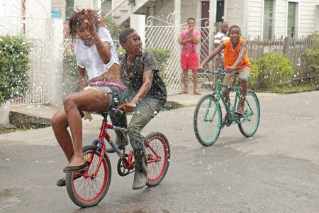 Splashed: Bikers in Albouystown reacting to a phagwah splash on Monday.