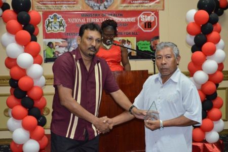 Lloyd Henrietto (right) receiving the award yesterday at the Pegasus Hotel for the most Outstanding Volunteer from Manager, National Tuberculosis Programme, Dr. Jeetendra Mohanlall (GINA photo)