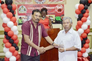 Lloyd Henrietto (right) receiving the award for the most Outstanding Volunteer from Manager, National Tuberculosis Programme, Dr. Jeetendra Mohanlall (GINA photo) 