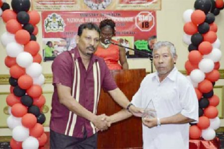 Lloyd Henrietto (right) receiving the award for the most Outstanding Volunteer from Manager, National Tuberculosis Programme, Dr. Jeetendra Mohanlall (GINA photo)