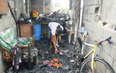 Nadira Johnson looks through the rubble in the aftermath of the fire