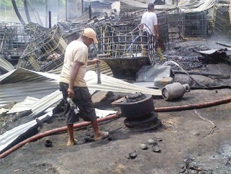 Residents going through the rubble of some of the buildings at Turn Basin, at the Port Kaituma waterfront in the aftermath of a fire started by a fuel boat explosion. 