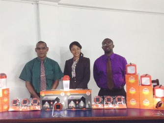 (L to R) Christopher Jacques, Chief Operations Officer, Holly Persaud, Public Relations Consultant and Dale Browne, Chief Executive Officer, all of Rehoboth Group, pose with a display of D.Light solar energy products.