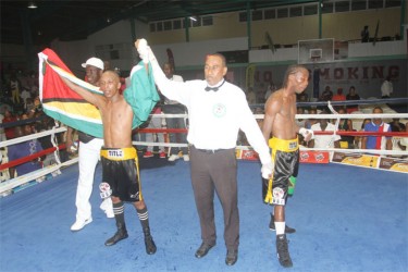 Dexter Marques’ hands are raised by the referee along with his trainer, Lennox Daniels following his unanimous victory over Jamaican, Rudolph Hedge on Saturday.  