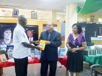 Deputy Vice-Chancellor Phillip DaSilva (left) formally receiving the collection from Sieyf Shahabuddeen while UG Librarian Gwyneth George looks on.