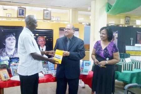 Deputy Vice-Chancellor Phillip DaSilva (left) formally receiving the collection from Sieyf Shahabuddeen while UG Librarian Gwyneth George looks on.