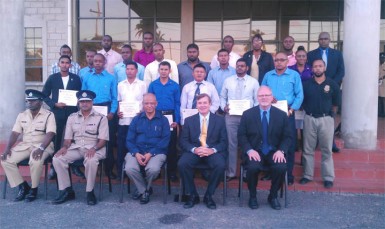 (From second left) Commissioner of Police Seelall Persaud, Minister of Home Affairs Clement Rohee, and US Ambassador Brent Hardt sit in front of the 21 graduates of the US Drug Enforcement Administration (DEA) airport interdiction course.