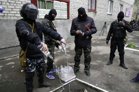 Masked men empty bottles of vodka to use them for petrol bombs in front of police headquarters in Slaviansk, yesterday. (Reuters/Gleb Garanich)
