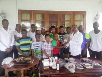 Michael Clarke handing over table tennis racquet to 11 years and under champion Kayson Ninvalle as other emerging players look on also in photo is extreme left, president of GTTA Godfrey Munroe, to his right GTTA’s Treasurer Deirdre Baynes-Edghill, extreme right Idi Lewis coach, to his right Linden Johnson Secretary of GTTA. 