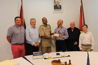 Dean Hassan (third from right) presenting the cheque to the acting Commissioner while other company investors look on. The child is the son of one of the investors. (Police photo) 