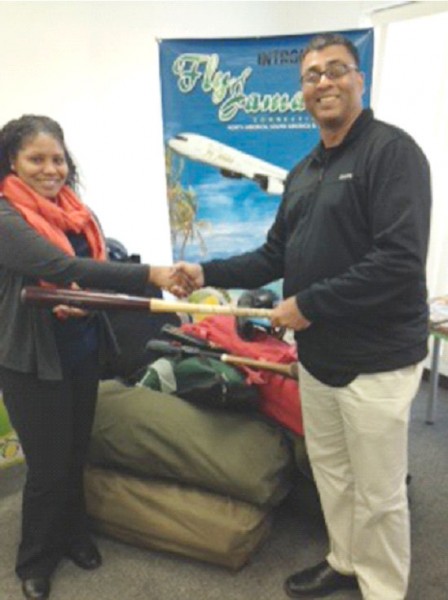 Guyana Softball League president Robin Singh (right) displays equipment acquired with Fly Jamaica representative Sarah Brown at the airline’s office in New York.