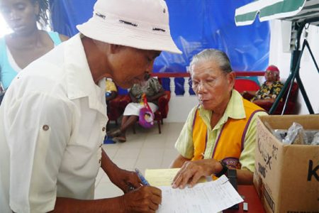 An elderly resident signs as she receives her free pair of glasses