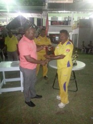 Everest Cricket Club President Stephen Lewis hands over several of the club’s Centennial magazine to Preysal Captain. 