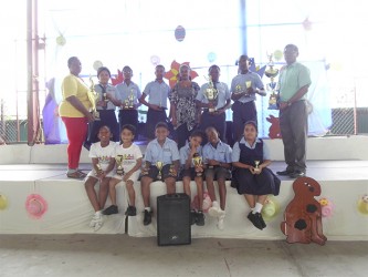 Trophy Stall representative Malenee Narine,centre along with Helena Ceasar, left and V Ouditt, head of Arawak Hose along with some of the prize winners at the Trophy Stall sponsored School of the Nations cricket competition which ended recently.