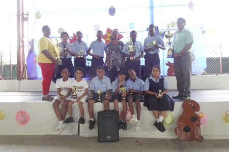 Trophy Stall representative Malenee Narine,centre along with Helena Ceasar, left and V Ouditt, head of Arawak Hose along with some of the prize winners at the Trophy Stall sponsored School of the Nations cricket competition which ended recently.
