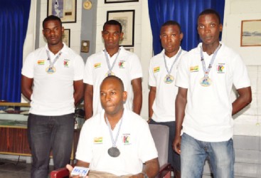 Men’s Indoor Hockey Captain Devin Munroe (sitting) surrounded by members of the national hockey team. 