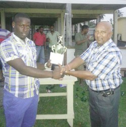 Tejnauth Jadunauth, Chairman of the Enmore Cricket Club hands over the prize which was sponsored by Trans Pacific and Woodpecker to Nichosie Barker. 