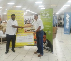 Tourism Minister Irfaan Ali receives the $2 million cheque from Managing Director of Courts Guyana, Clyde De Haas