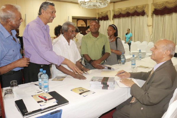 Former Chairman of Demerara Distillers Limited, Dr Yesu Persaud signing copies of his autobiography `Reaching for the Start; The Life of Yesu Persaud Vol 1’ at its launching yesterday at the Pegasus Hotel. The first volume is an introduction to Persaud’s life from his early childhood to his school days and ends in 1976. 