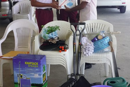 Representatives from Global Youth Movement – Guyana presenting a gift of agricultural tools to representatives from secondary schools in Region Five 