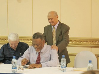 Dr Yesu Persaud (standing) in a humorous exchange with Prime Minister Sam Hinds (sitting at right) and Dr Ian McDonald.