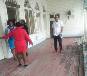 Carol Sooba (left with back to camera) talking with her staff as her bodyguard Sean Hinds (right) looks on. 