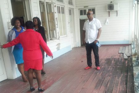Carol Sooba (left with back to camera) talking with her staff as her bodyguard Sean Hinds (right) looks on. 
