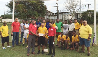 Scotiabank’s representatives presenting the sponsorship cheque to one of the programme’s participants, Daniel DeAbreau yesterday at the rugby field. 