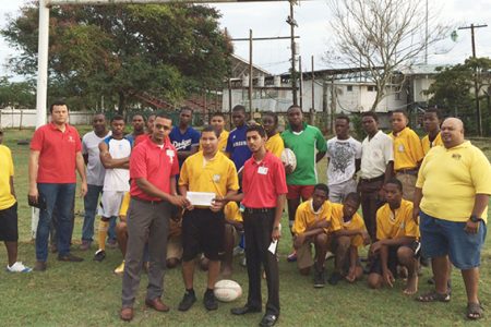 Scotiabank’s representatives presenting the sponsorship cheque to one of the programme’s participants, Daniel DeAbreau yesterday at the rugby field.
