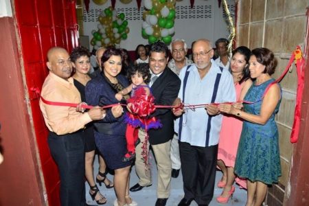 President Donald Ramotar (third from right) assists in cutting the ribbon to officially open Sueria Manufacturing Inc.  Also in photo are Joint CEOs of the company, Teshawna Lall (second from left) and Frank Sanichara, baby Sueria (centre), First Lady Deolatchmee Ramotar (right) and Kaieteur News’ Publisher Glenn Lall (left) (GINA photo)
