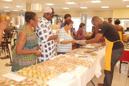 Courts Marketing Manager Pernell Cummings yesterday handing out delicacies to customers showcasing what could be done with home appliances.